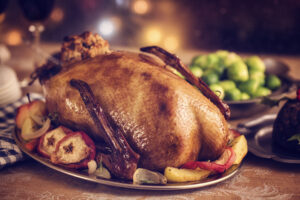 Traditional British holiday goose dinner with apples, brussels sprouts and Christmas Pudding